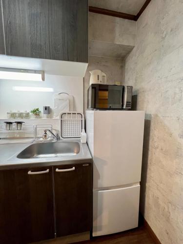 a kitchen with a white refrigerator and a sink at ペットと泊まれる Tatami & B 池上 202 2DK 40m2 in Tokyo
