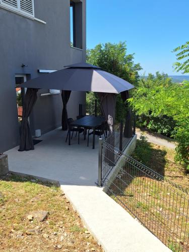 a patio with a table and an umbrella at Apartment Vidak in Labin