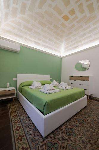 a bedroom with a large bed with green sheets at Domvs Cementina con vista mare in Trapani