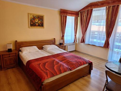 a bedroom with a bed and a table and windows at SNOW PEAK TODORKA AND VIHREN APARTAMENT /NEXT TO THE LIFT/ 7 PERSONS/ in Bansko