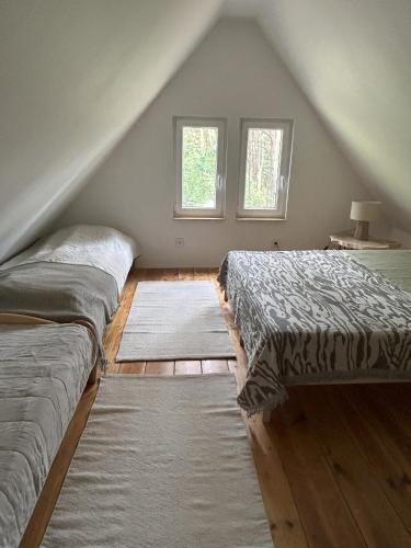 a attic bedroom with two beds and a window at Dom w lesie in Dzbądzek