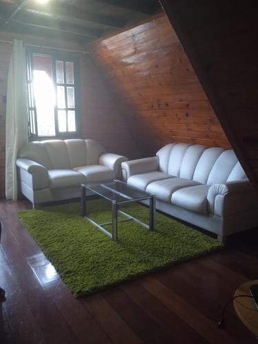 a living room with white couches and a green rug at Pousada Chale Pico da Bandeira in Alto Caparao