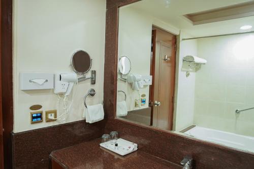 a bathroom with a mirror and a sink and a tub at Clarion Bella Casa at Airport in Jaipur