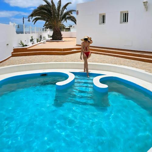 a woman in a hat standing next to a swimming pool at Blue Miracle Villa in Arrecife
