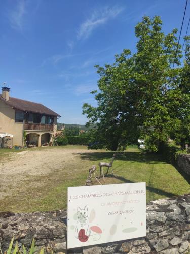 a sign in front of a yard with a house at Les chambres des chats malicieux in Cajarc