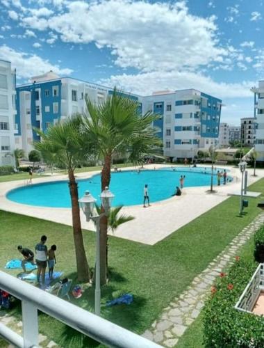 a large swimming pool with palm trees and buildings at Warda luxury home in Martil