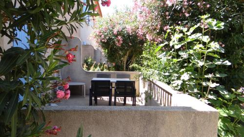 a table and chairs in a garden with flowers at Résidence L'Orangeraie-2-Claira 66530 in Claira