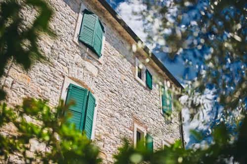 a brick building with green shutters on it at Casa Romantica La Parenzana in Buje