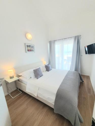 a bedroom with a large white bed and a window at Apartments Marti in Murter