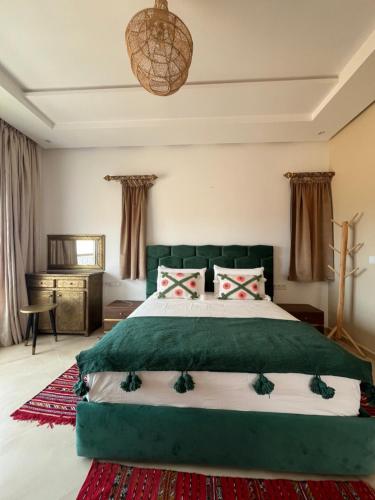 a bedroom with a large bed with a green headboard at Riad Tammam in Essaouira