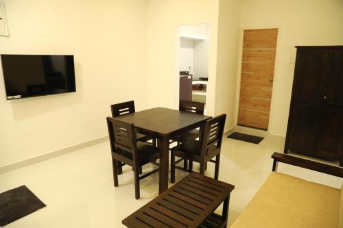 a dining room with a table and chairs and a television at F-3 Tulsi By The Peace in Chennai