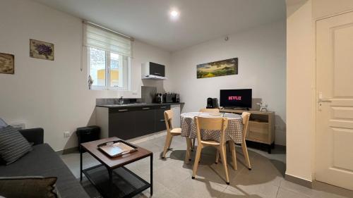 a living room with a table and a kitchen at Fenix Appartement T2 40 M2 cosy RDC plein centre ville in Pierrelatte