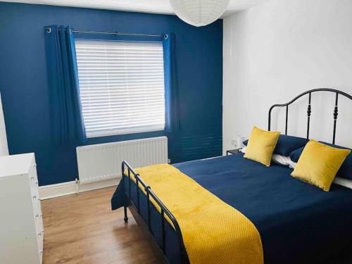 a blue bedroom with a bed with yellow sheets and a window at Entire 2 bedroom flat Northumberland in Blythe