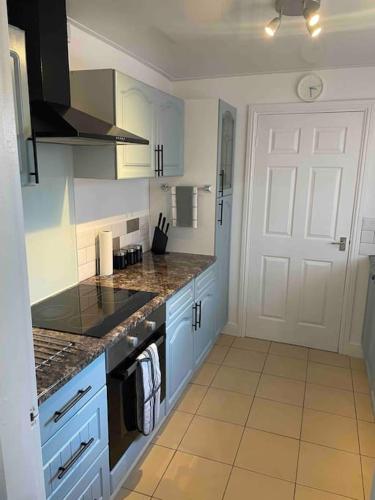 a kitchen with blue cabinets and a white door at Entire 2 bedroom flat Northumberland in Blythe