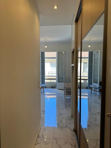 un couloir avec un sol en marbre et une porte vitrée dans l'établissement Agora, à Nice