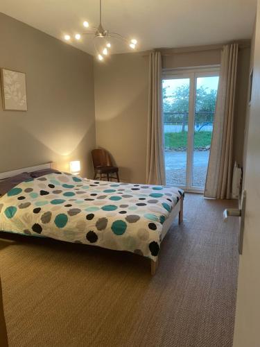 a bedroom with a bed with a comforter and a window at Pied à terre au coeur des écuries in Paley