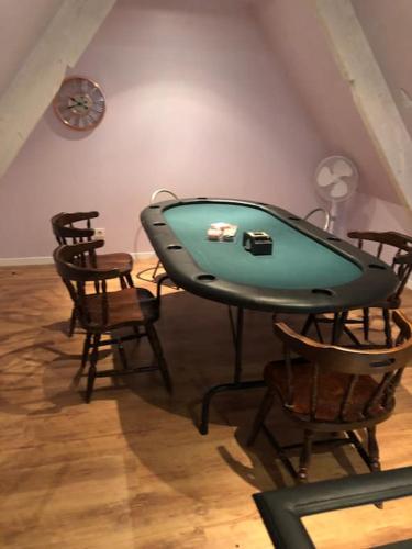 a pool table in a room with chairs and a clock at Maison avec piscine in Pommérieux