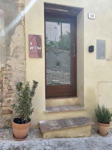 a front door of a house with two potted plants at A dormì in Serra deʼ Conti