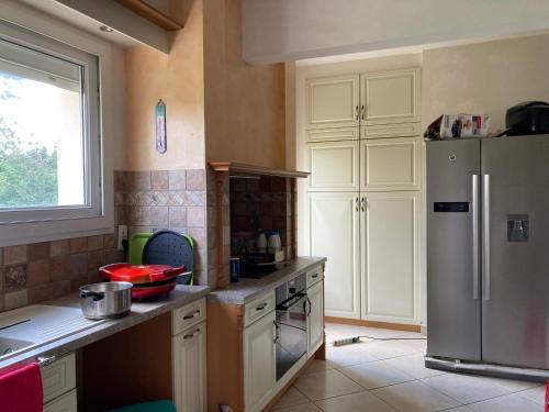 a kitchen with white cabinets and a refrigerator at Grande maison avec un grand jardin in Auneau