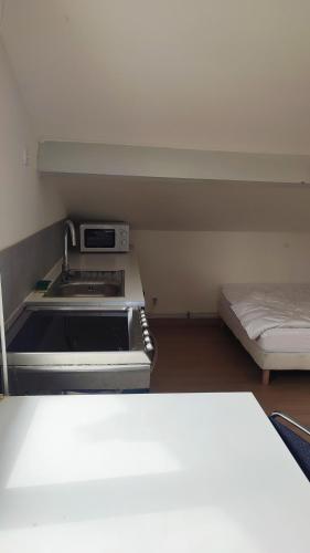 - une cuisine avec cuisinière et un lit dans une chambre dans l'établissement Studio Pour Une deux Personnes, à La Courneuve