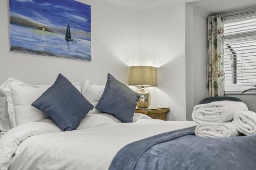 a bedroom with a white bed with blue pillows at Upper Rock Brighton Apartments in Brighton & Hove