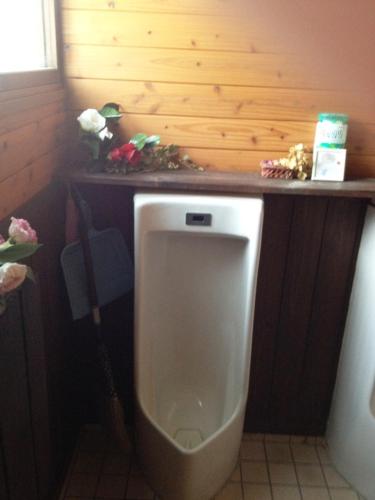 a urinal in a bathroom with a wooden wall at Minshuku Yomoshirou in Nanto