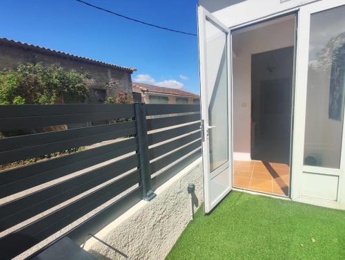 a fence with a door open to a yard with grass at Gîte Le Sallèles in Sallèles-dʼAude