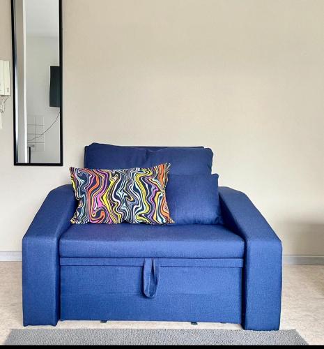 a blue couch with two colorful pillows on it at LENASTAY I Modernes Apartment-Studio near Uni in Kaiserslautern