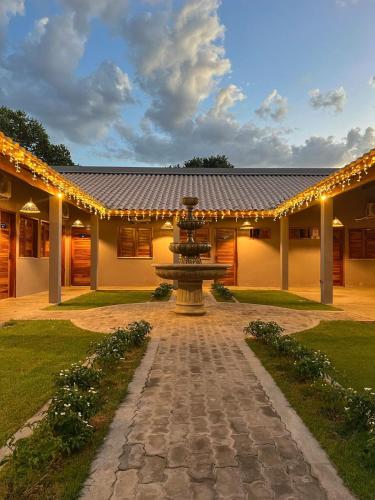 a fountain in front of a building with lights at Hotel do Carmo in Piracuruca