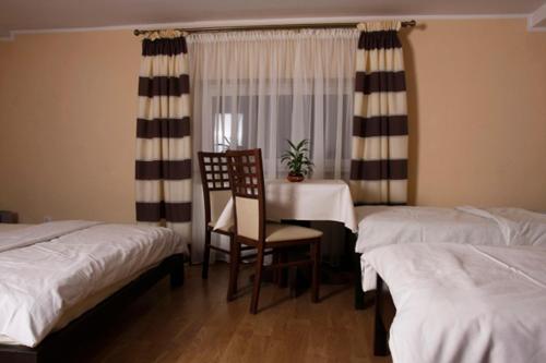 Habitación con 2 camas, mesa y silla en Euro Zajazd - Casa Di Fulvio Maria Viola, en Bielsko-Biala