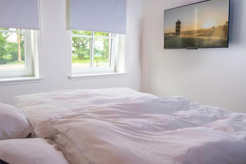 a white bed in a white room with windows at Ferienwohnung Frohsinn im historischen Gulfhof in Krummhörn