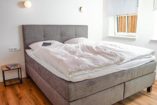 a large bed with white sheets on it in a bedroom at Ferienwohnung Frohsinn im historischen Gulfhof in Krummhörn