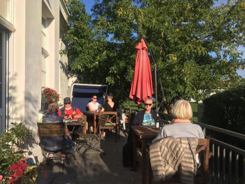 a group of people sitting at tables under an umbrella at Hotel Prinzenpalais Bad Doberan in Bad Doberan