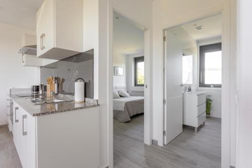 a white kitchen with a sink and a bedroom at Apartamentos A Chousa in Valdoviño