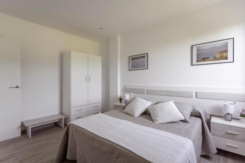 a white bedroom with a large bed with two pillows at Apartamentos A Chousa in Valdoviño