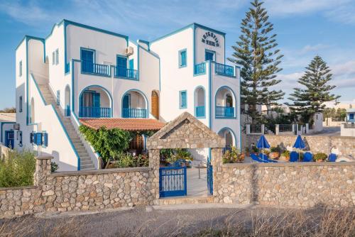 a large white building with a stone wall at Villa Margarita in Karterados