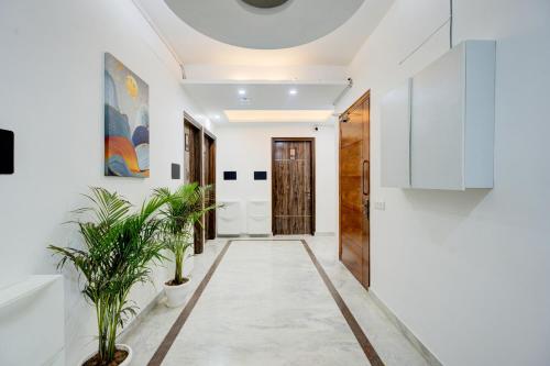 a corridor with white walls and a hallway with plants at The Empire Studioz Hotel Golf Course Road Studio with Kitchen & Balcony One Horizon Center Paras Hospital Cyber City in Gurgaon