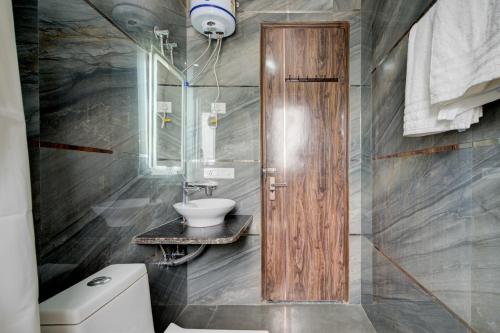 a bathroom with a wooden door and a sink at The Empire Studioz Hotel Golf Course Road Studio with Kitchen & Balcony One Horizon Center Paras Hospital Cyber City in Gurgaon