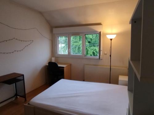 une chambre avec un lit, un bureau et une fenêtre dans l'établissement Le8bis, à Saint-Denis