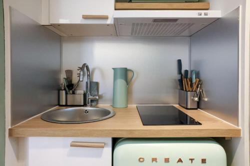 - un comptoir de cuisine avec évier et ustensiles dans l'établissement WiFi AC 5 mins from the Croisette, au Cannet