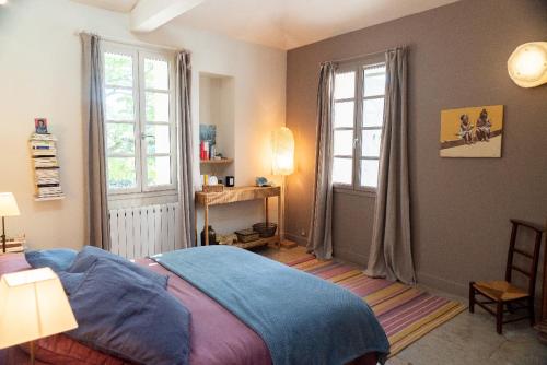 une chambre avec un lit et deux fenêtres dans l'établissement Mas de la Chamberte, à Montpellier