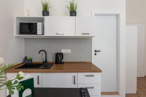 a kitchen with white cabinets and a sink and a microwave at U Mamlasů in Brno