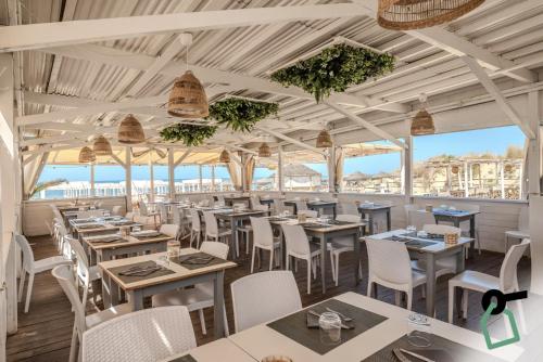 a restaurant with tables and chairs and the ocean in the background at HOTIDAY Room Collection - Tirrenia in Tirrenia