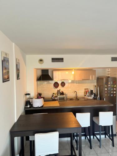 - une cuisine avec une table en bois et des chaises blanches dans l'établissement Agréable appartement climatisé devant la mer avec parking, à Antibes