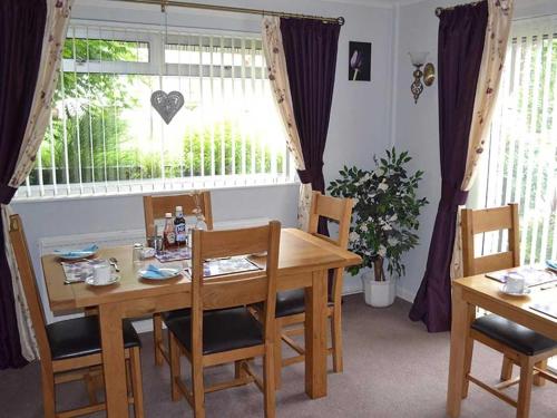Un comedor con mesa y sillas y una ventana. en Gwynfa, en Porthmadog