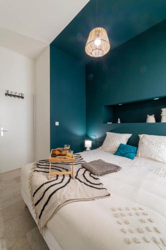 une chambre avec un grand lit avec un mur bleu dans l'établissement le Nîmois Appart Clim MaisonCarréeConciergerie, à Nîmes