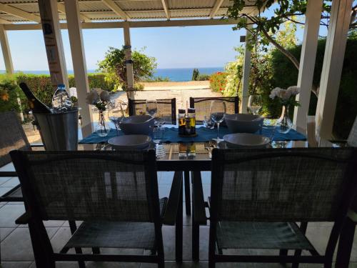 a table on a porch with two chairs and a table with wine glasses at Ocean Pearl in Peyia