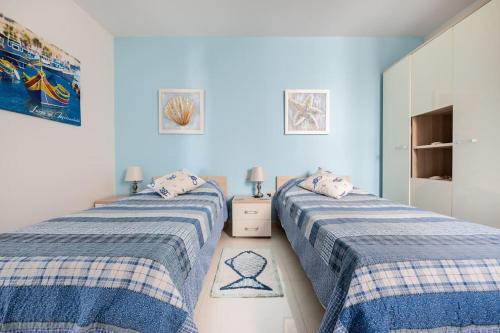 two beds sitting next to each other in a room at Seagull Penthouse Marsaxlokk in Marsaxlokk