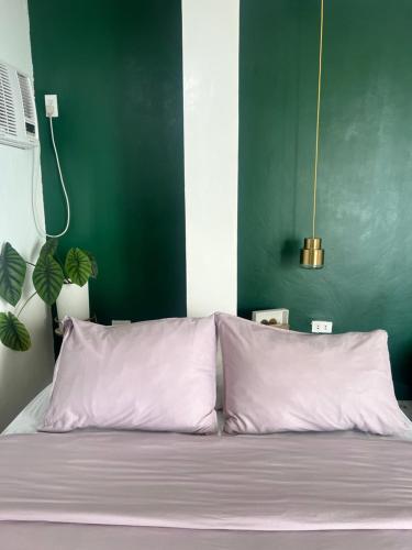 a bed with two white pillows and a green wall at Bintana sa Paraiso Binunsaran in Mambajao
