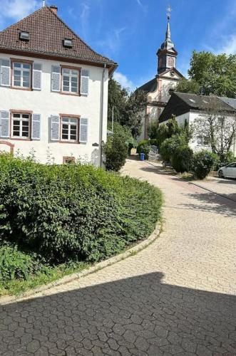a large white house with a steeple and a church at Gemütliches Scheunenfachwerkhaus nahe Frankfurt mit Glasfaser und Klima in Bad Soden am Taunus